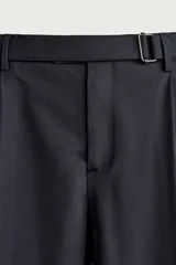 Pantalón de corte regular fit confeccionado en tejido con lana. Presenta cintura ajustable con cinturón integrado, pliegues frontales, bolsillos laterales y bolsillos traseros de doble vivo. Cierre frontal con cremallera y botón.
