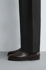 Bota estilo Chelsea de cuero negro, con elásticos laterales y suela plana a tono con ligero tacón.