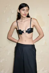 Top bustier negro de cuero ecológico con tirantes finos ajustables y cierre frontal con hebilla metálica.