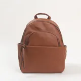 Mochila de cuero sintético color marrón con textura granulada, diseño redondeado, cierre frontal con cremallera y bolsillo exterior.