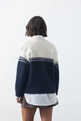 Cardigan de tejido jacquard en color azul marino y blanco, con diseño de conejitos en los laterales, cierre frontal con botones y cuello redondo.