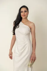 Vestido largo de fiesta color marfil/champagne, confeccionado en lurex. Diseño drapeado con un solo hombro.