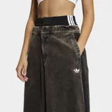 Pantalón de corte holgado confeccionado en tejido de corderoy, con diseño de cintura alta y cierre frontal con botones. Presenta una estética urbana con franjas laterales características de la marca.