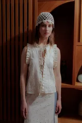 Chaleco color crema con bordado calado, cuello mao, cierre frontal con lazos y volados en sisas y ruedo.