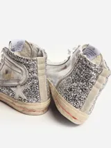 Zapatillas deportivas de caña alta plateadas con glitter, estrella blanca y suela color crema.