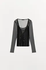 Top de tul semitransparente de color negro, con diseño de doble capa que incluye un top interior con escote en pico y una chaqueta de manga larga con cierre frontal de gancho metálico.