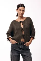 Saco de punto gris con frente abierto, cierre mediante lazos frontales y mangas con puños elásticos. Presenta una textura suave y un diseño de volumen holgado.