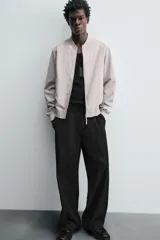 Cazadora bomber ligera de tejido técnico color verde oliva, con cuello, puños y bajo en rib elástico. Presenta cierre frontal de cremallera y bolsillos de vivo en la cadera.