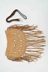 Cartera de gamuza color camel con diseño semicircular, decorada con flecos largos en el borde y tachas metálicas plateadas en la parte frontal. Incluye una correa larga ajustable y extraíble.