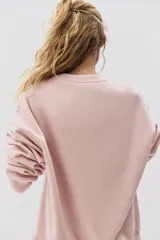 Buzo de tejido de punto color rosa pálido, con cuello redondo, hombros caídos y puños y bajo acanalados.