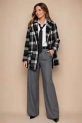Chaqueta de corte recto con diseño a cuadros en tonos blanco y negro, confeccionada en lana. Presenta solapas clásicas, cierre frontal y bolsillos laterales con ribete en contraste.