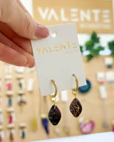 Aros colgantes con aro dorado y dije en forma de gota color borgoña con detalles dorados.