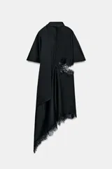Vestido midi de satén negro con cuello subido, manga corta tipo capa y pañuelo incorporado en el mismo tejido. Presenta aberturas laterales decoradas con encaje a tono y bajo asimétrico con detalles de encaje. Cierre en la espalda con abertura y botones forrados.