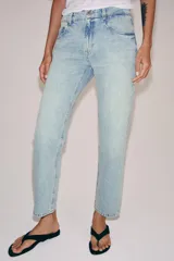 Jeans de tiro medio con corte slim leg, confeccionados en denim de lavado claro. Presentan diseño clásico de cinco bolsillos, cierre frontal con cremallera y botón, y cintura con trabillas.