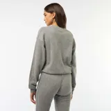 Buzo de punto de textura suave y gruesa, color gris, con cuello redondo y mangas largas con puños elásticos.
