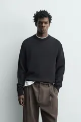 Sweater de punto negro de corte regular fit, confeccionado en algodón con cuello redondo, manga larga y acabados en rib.