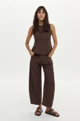 Top de lino color beige con cuello bote y diseño con peplum, sin mangas y con cierre invisible en la espalda.