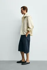 Parka cropped fit de tejido técnico ligero color beige, sin forro interior, con cuello solapa, capucha desmontable y manga larga. Cuenta con bolsillos de solapa en la cadera y cierre frontal con cremallera oculta por solapa con botones a presión.