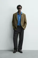 Blazer regular fit de Zara Origins, confeccionada en tejido de lana y algodón color verde militar. Presenta cuello con solapas de muesca, cierre frontal de un botón, bolsillos de solapa en la cadera y bolsillo de vivo en el pecho.