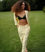 Pantalón zanahoria de tiro alto color amarillo pálido, confeccionado en viscolino con 15% de lino, con trabillas en la cintura, solapas con botón abajo de la cintura, pliegues y cierre tradicional.