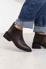 Botineta de cuero vacuno color marrón oscuro, con diseño texturizado, elásticos laterales recubiertos de gamuza, punta perfilada y taco cuadrado de 5 cm.