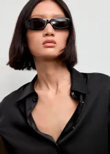 Camisa de poliéster con acabado satinado, color negro, de manga larga con puños abotonados, diseño recto, cuello camisero y cierre delantero con botones.