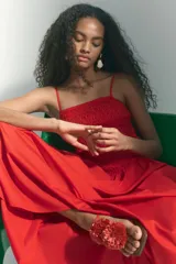 Vestido maxi rojo confeccionado en tejido liviano de algodón, con escote recto, breteles finos y cuerpo fruncido en nido de abeja con costura en V en la cintura, y falda larga con vuelo.