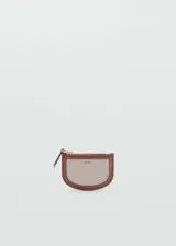 Monedero ovalado de tejido canvas color beige con ribete de cuero marrón. Tiene cierre de cremallera y logo en relieve.