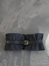 Cinto ancho tipo fajín confeccionado en cuero genuino de color negro, con diseño fruncido y hebilla metálica dorada frontal.