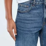 Jean de corte regular con diseño clásico de cinco bolsillos, confeccionado en denim azul con acabado ligeramente desgastado.