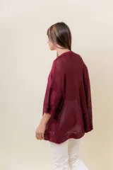 Buzo de tejido liviano con brillo sutil tipo lurex, color beige o dorado claro. Presenta un calce suelto (oversize) con mangas amplias y cuello redondo. El ruedo tiene un detalle de terminación festoneado con pequeños calados.