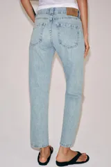 Jeans de tiro medio con corte slim leg, confeccionados en denim de lavado claro. Presentan diseño clásico de cinco bolsillos, cierre frontal con cremallera y botón, y cintura con trabillas.