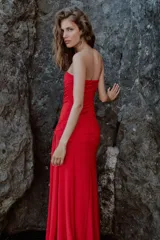 Vestido largo de fiesta color rojo, con escote corazón y diseño palabra de honor. Presenta detalles de drapeado lateral y una superposición de tela con lazada en la cintura, con falda de corte evasé.