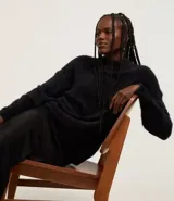 Suéter de punto negro con cuello redondo y mangas largas ajustadas. Diseño slim alargado con efecto de pelitos.