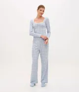 Pijama de dos piezas confeccionado en tejido rib con estampado de cuadros. La blusa es de manga larga, con escote cuadrado decorado con encaje y detalle fruncido en el busto. El pantalón presenta corte recto y cintura elástica.