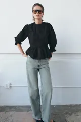 Camisa de algodón con cuello redondo, manga tres cuartos con puño elástico y volante. Presenta detalles de flores bordadas a tono, entredoses y cierre posterior con abertura y botón.