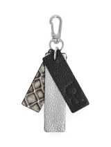 Llavero con mosquetón plateado y tres tiras colgantes de cuero sintético: una negra con textura y logo grabado, una plateada con textura y una con estampado de piel de cocodrilo en tonos beige y marrón.