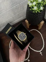Reloj Casio Quartz con caja cuadrada y correa de eslabones en tono dorado. La esfera es de color negro con manecillas y marcadores de hora dorados, y cuenta con una ventana de fecha.