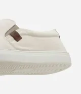 Championes tipo slip on marca Viko, de color negro con suela de goma blanca. Presenta un diseño minimalista sin cordones con paneles elásticos laterales y un pequeño detalle de etiqueta en color marrón.
