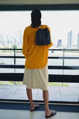 Bolso de hombro tipo saco confeccionado en piel azul marino, con detalle de pespuntes blancos verticales, asas finas de hombro en color blanco y cierre fruncido.