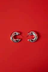 Aros tipo argolla de diseño chunky, con acabado plateado brillante y forma redondeada.