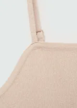 Top de punto fino color beige, con escote cuadrado y tirantes finos. Presenta un diseño entallado y corto.