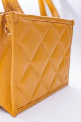 Cartera pequeña color beige, con diseño acolchado en forma de rombos. Tiene doble asa corta y correa larga desmontable y regulable.