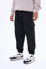 Pantalon cargo negro de corte holgado, con bolsillos laterales con solapa y puños elásticos en los tobillos. Cuenta con cintura elástica con cordón de ajuste.