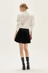 Falda corta de terciopelo negro con diseño ajustado en la cadera y volado en el ruedo.