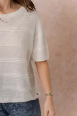 Sweater tejido celeste de manga corta con textura y delicadas líneas horizontales en relieve. Presenta cuello redondo y calce amplio con hombros caídos.