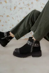 Bota corta de gamuza marrón con puntera de cuero liso, suela track negra y correa desmontable con tachas metálicas.