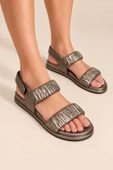 Sandalias de cuero color plateado, con dos tiras delanteras fruncidas, suela baja y tira en el talón con cierre de velcro.