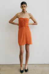Vestido corto strapless color naranja, con frunce en el frente y falda semi acampanada.