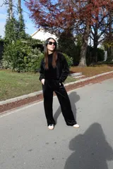 Conjunto de dos piezas confeccionado en tejido plush aterciopelado color negro. Incluye un buzo de corte cropped con cuello redondo y mangas largas, y un pantalón estilo cargo de silueta holgada con bolsillos laterales funcionales y puños ajustables en los tobillos.